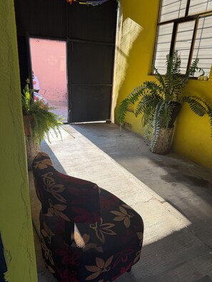 A narrow hallway with a bench, potted plants, and a door leading to an outdoor area.