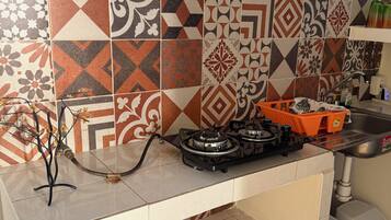 Une cuisine équipée d’une cuisinière à gaz, d’un évier et d’un plan de travail recouvert de carreaux.