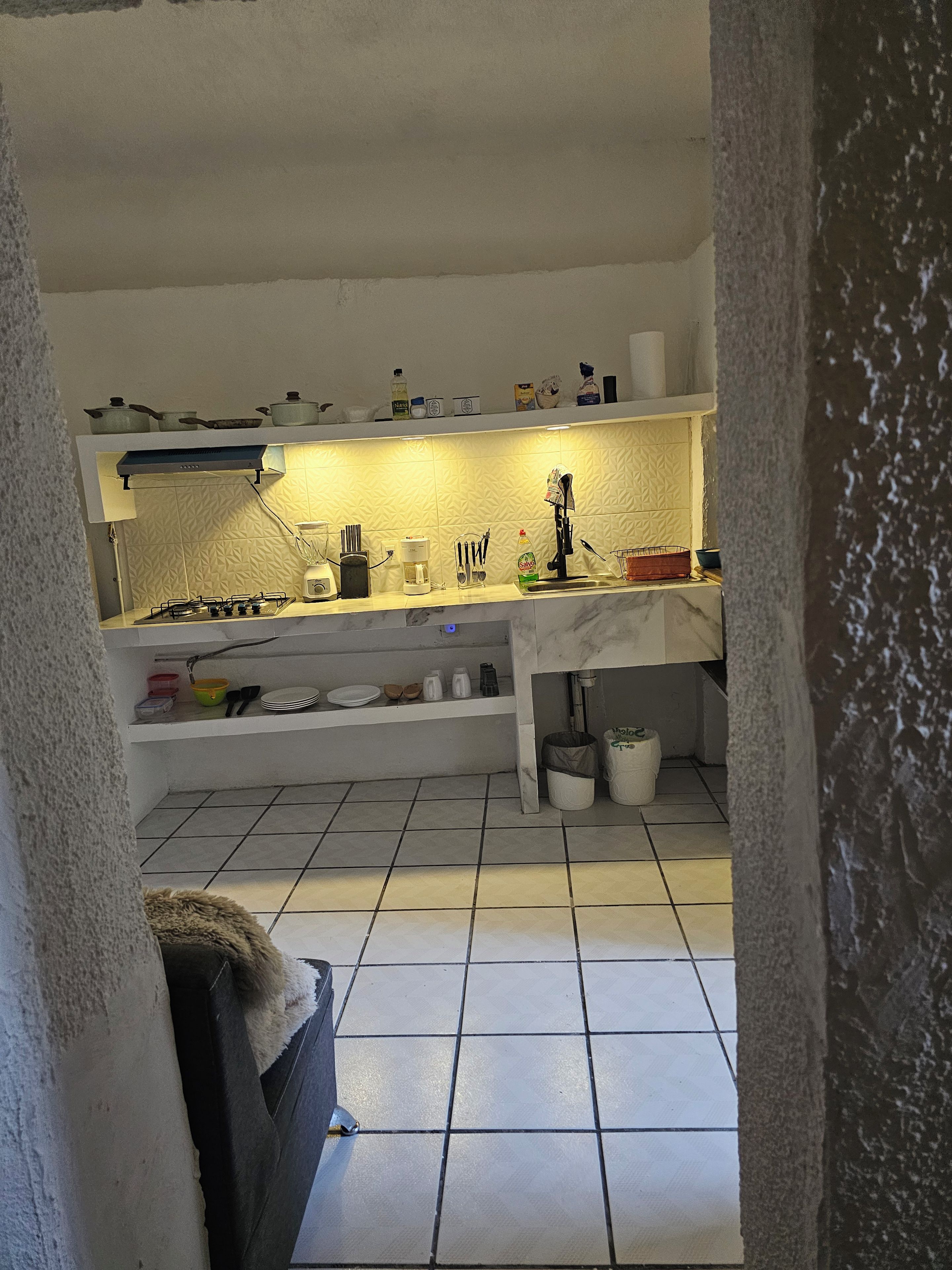 Una cocina con estufa a gas, armarios blancos y salpicadero de azulejos.