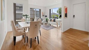 A modern interior with a dining area, a sofa, and a view of the outdoors.