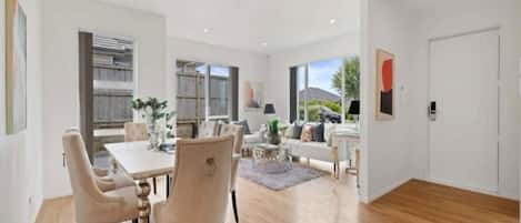 A modern interior with a dining area, a sofa, and a view of the outdoors.