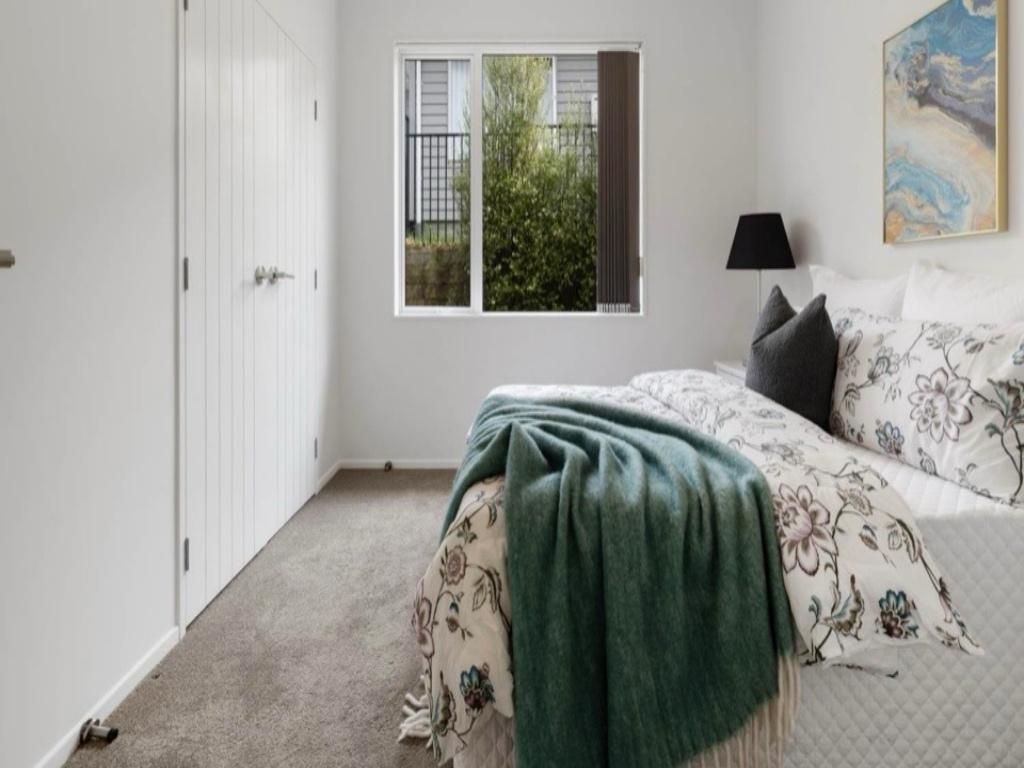 Un dormitorio con cama, ventana, puerta y un cuadro en la pared.