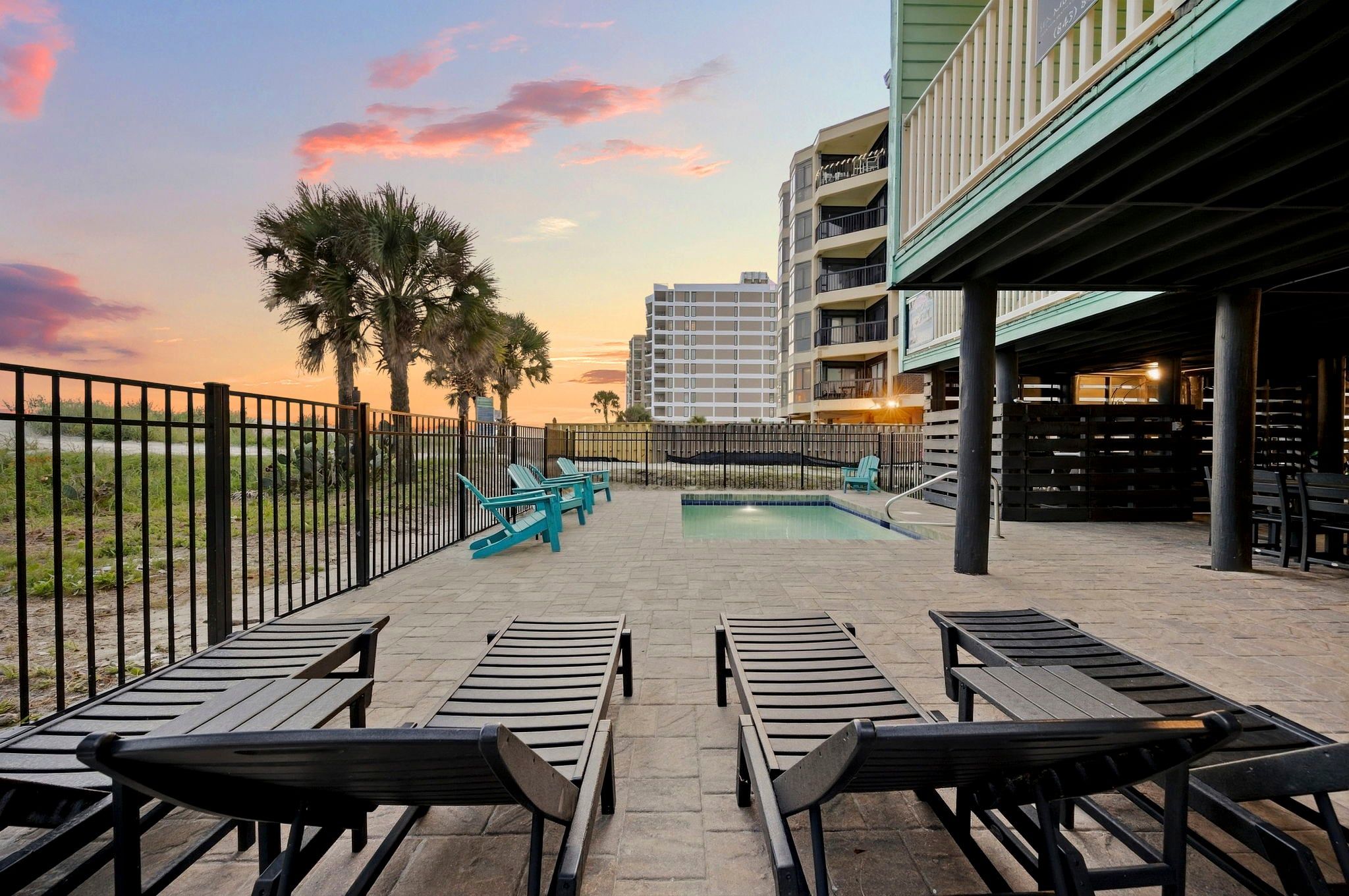 A poolside area with lounge chairs and a building in the background.