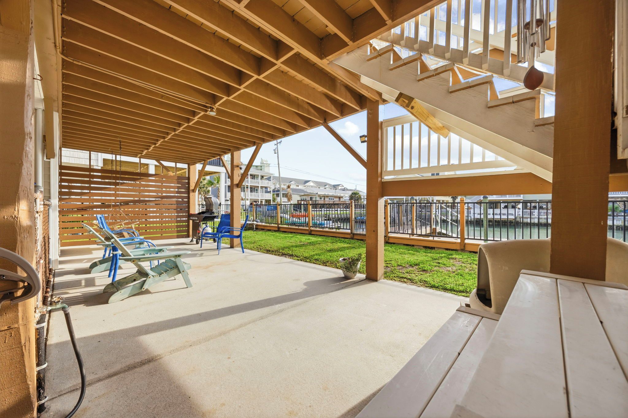 Un patio al aire libre con una pérgola de madera, zona de estar y vistas al agua.