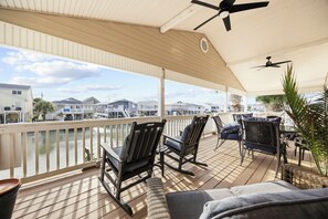 Eine überdachte Terrasse mit Stühlen und Tisch, mit Blick auf eine Marina mit Booten und Gebäuden.