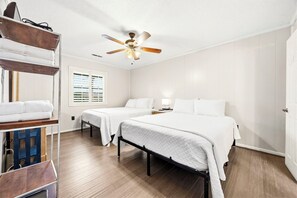 A hotel room with two beds, a ceiling fan, a window with blinds, and a wooden floor. - Salty Breeze - Cozy 4BR Beach House w/ Private Dock (Sleeps 10) (North Myrtle Beach)