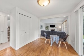 A modern living room with a fireplace, a flat-screen TV, and a dining area with a table and chairs. - Tech-Ready Suite @ Education Hill | Fast WiFi & AC (Redmond)