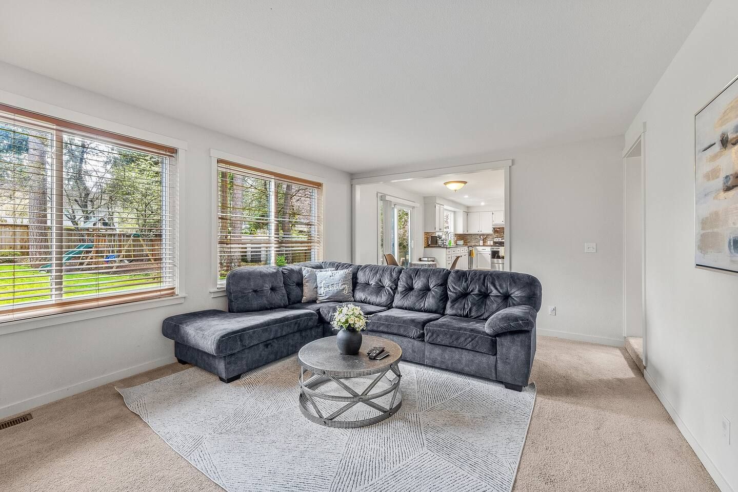 A modern living room with a sectional sofa, a round coffee table, and a patterned rug.