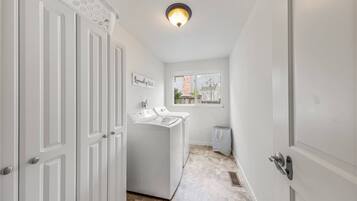 A laundry room with a washing machine, a drying rack, and a sign that reads 'Laundry 5'.