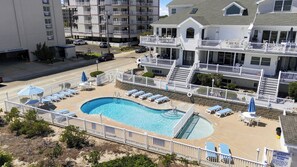 A residential building with a swimming pool, multiple balconies, and a gated entrance. - Spacious 4BR Wildwood Crest Home with 3 Private Decks & Garage Parking (Wildwood Crest)