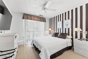 A bedroom with a bed, a ceiling fan, a window with blinds, a nightstand, a lamp, and a wall-mounted TV. - Spacious 4BR Wildwood Crest Home with 3 Private Decks & Garage Parking (Wildwood Crest)