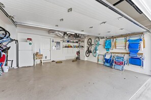 A garage with bicycles, a refrigerator, and various storage items. - Spacious 4BR Wildwood Crest Home with 3 Private Decks & Garage Parking (Wildwood Crest)