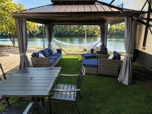 Une terrasse extérieure dotée d’un espace salon abrité, d’une table et de chaises.