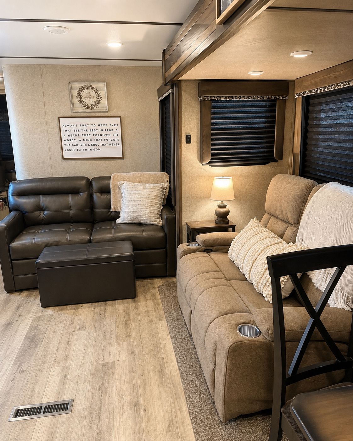A cozy RV interior with a brown leather sofa, a beige couch, and a small table with a lamp.