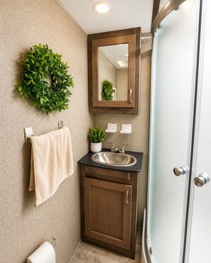 Une salle de bain équipée d’un lavabo, d’un miroir, d’un porte-serviettes et d’une porte de douche.