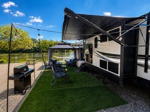 A recreational vehicle with a covered outdoor area, a grill, and a tent. - Rivers Edge Retreat at River Rock Landing (Gadsden)