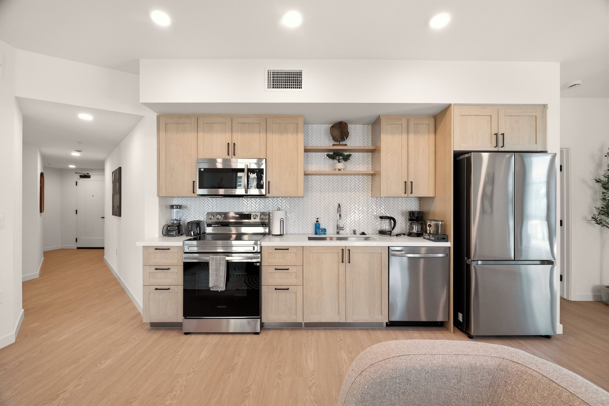 Een moderne keuken met roestvrijstalen apparatuur, houten kastjes en een backsplash van visgraatmozaïek.