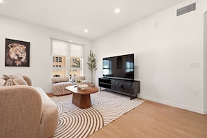 A modern living room with a flat-screen TV, a coffee table, sofas, and a patterned rug. - Modern King 2B2B｜Pool & Gym｜70in Smart 4K TV (Montclair)