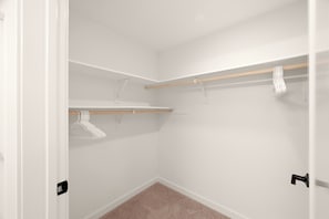 A walk-in closet with white walls, a wooden floor, and a door with a black handle. - Modern King 2B2B｜Pool & Gym｜70in Smart 4K TV (Montclair)