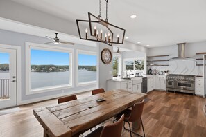 A spacious kitchen with a large island, modern appliances, and a view of a lake. - 7BR Lake View Escape, Hot Tub, Lake Views & Game Room (Lake Ozark)