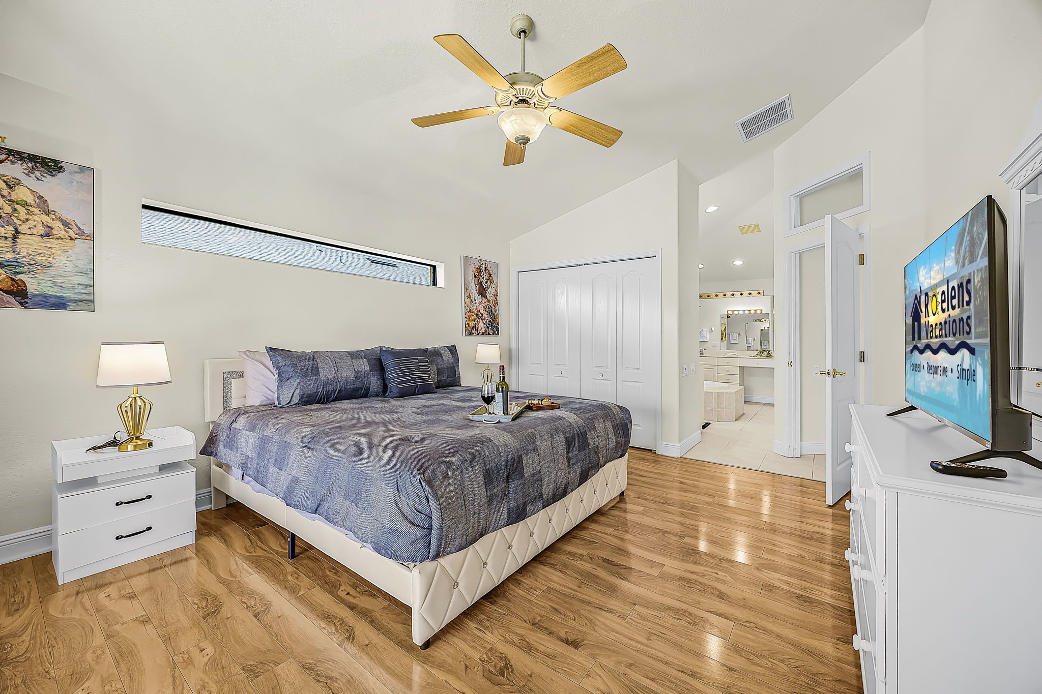 A bedroom with a bed, bedside tables, a ceiling fan, and a TV.