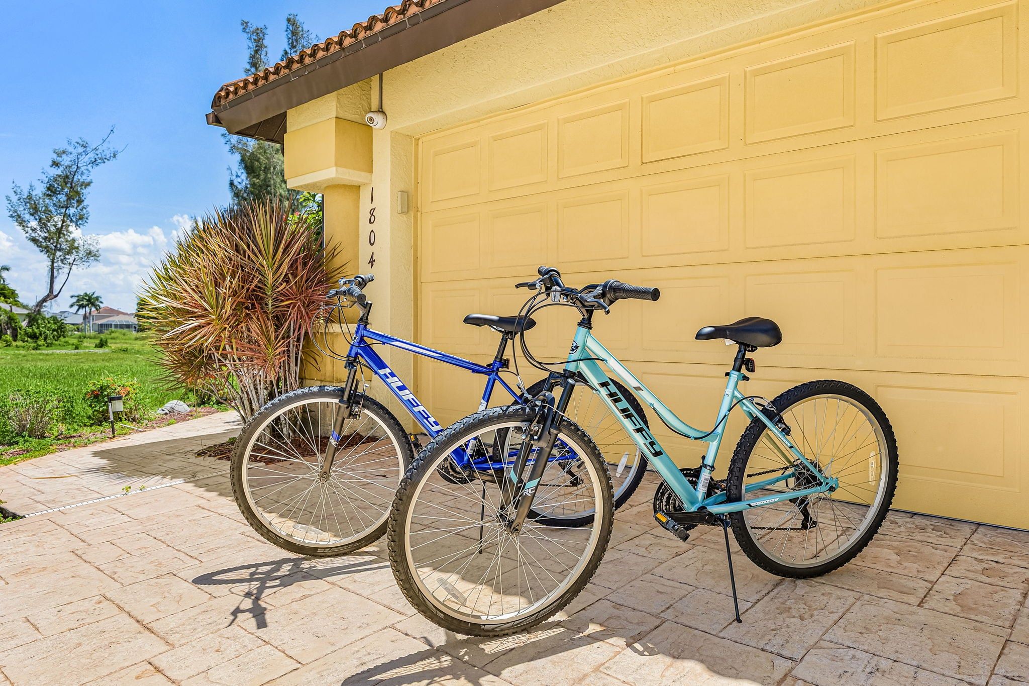 Two bicycles parked in front of a yellow garage door.