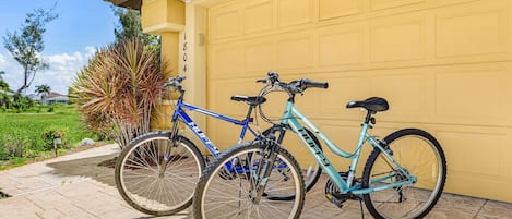 Two bicycles parked in front of a yellow garage door.