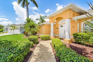 A residential building with a paved driveway, a well-maintained lawn, and a palm tree. - Tropical Canal Escape with Pool, Spa & Kayaks in Cape Coral - Pineapple Princess - Roelens (Cape Coral)
