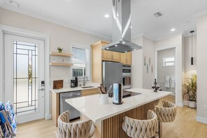A modern kitchen with a central island, stainless steel appliances, and wooden cabinetry. - Poolside Fun, Pickleball & Coastal Adventures Await in Fort Myers - Jefferson Palms - Roelens (Fort Myers Beach)