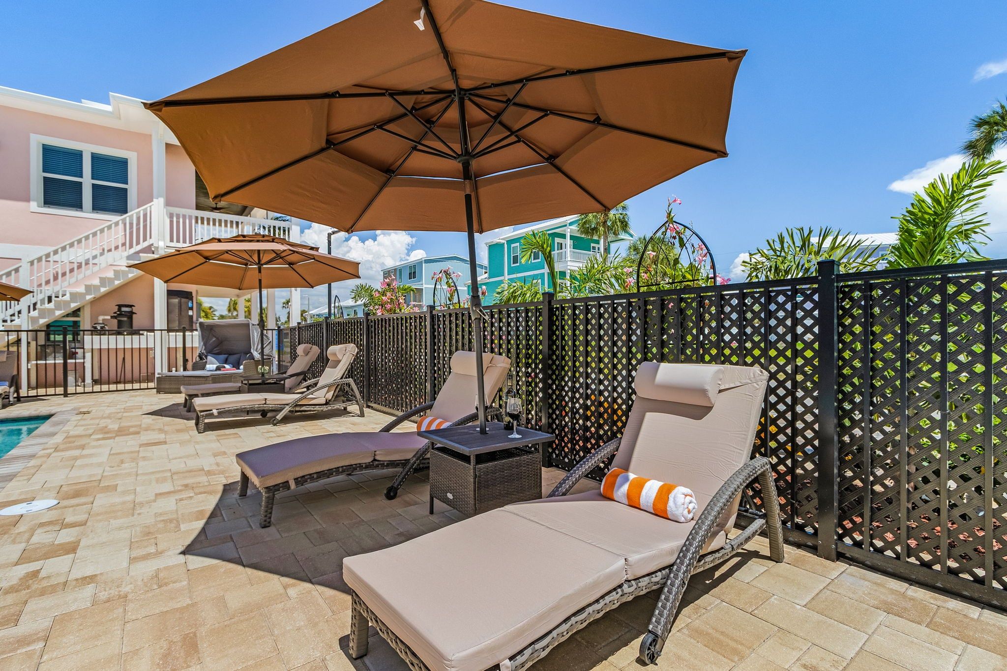 A poolside area with lounge chairs, umbrellas, and a pool.