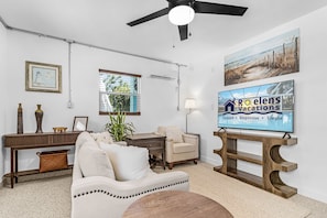 A living room with a sofa, armchair, coffee table, and a TV mounted on a wooden stand. - Poolside Fun, Pickleball & Coastal Adventures Await in Fort Myers - Jefferson Palms - Roelens (Fort Myers Beach)