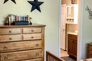 A wooden dresser with drawers, a star decoration on the wall, and a doorway leading to a bathroom with cabinets and a mirror. - Tiger Den - Sugar Mountain, pool table, views (Banner Elk)