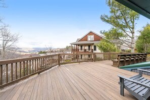 Une terrasse en bois offrant une vue sur une maison et des montagnes.