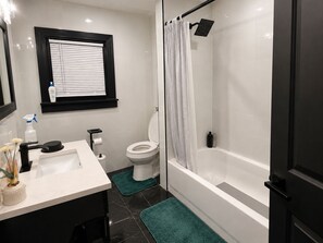 Et badeværelse med toilet, vask og brusebad.