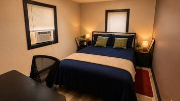 A compact hotel room with a single bed, bedside tables with lamps, a desk, and a chair.