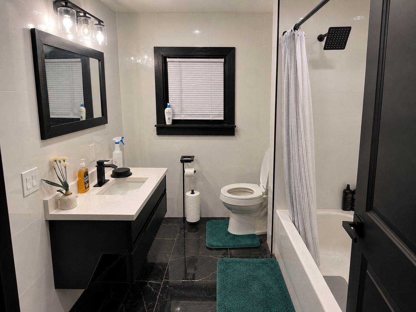 A modern bathroom with a white sink, black vanity, a toilet, and a shower area.