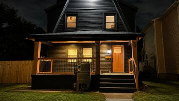 A two-story house with a front porch, a visible mailbox, and a number '990' on the side.