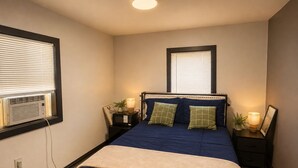Une chambre à coucher comprenant un lit, des tables de chevet, des lampes et un radiateur fixé au mur.