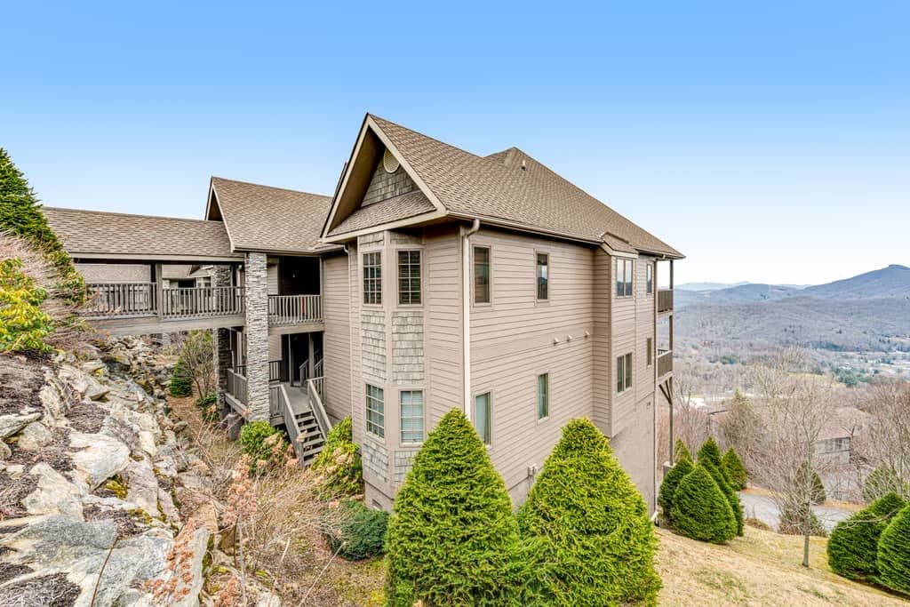 A two-story building with a stone foundation, a balcony, and a view of the surrounding landscape.