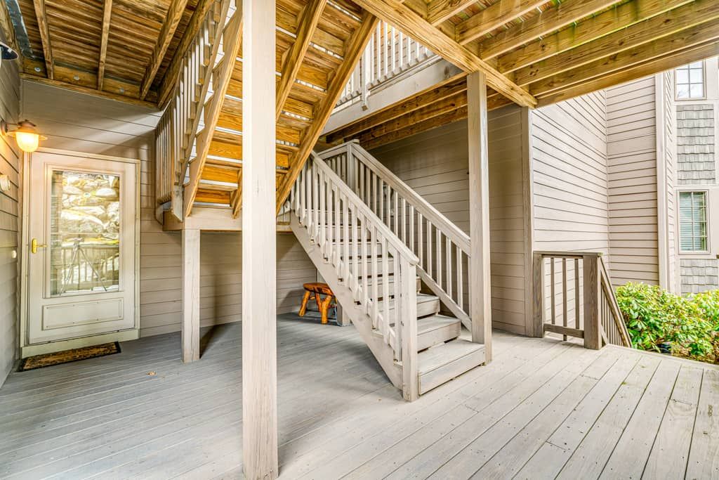Una terraza de madera con una escalera que lleva a un segundo piso.