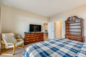 Une chambre à coucher comprenant un lit, une télévision, une commode en bois et une chaise.