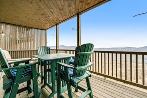 Une terrasse en bois avec une table et des chaises, offrant une vue sur un paysage montagneux.