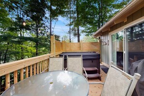 Eine Terrassenausstattung mit Glastisch, Stühlen und einem Whirlpool.