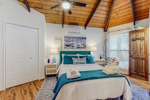 A bedroom with a bed, a ceiling fan, a window with blinds, a door, and a wall-mounted air conditioner. - The Beech Hut: 2br pet friendly roundhouse on Beech Mtn with hot tub, firepit, & fenced yard! (Beech Mountain)