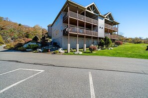 A two-story building with a balcony on the second floor, situated on a grassy hill with a clear sky. - A Sweet Escape: 2br Condo in The Reserve on Sugar Mtn - Long Range Views! (Sugar Mountain)
