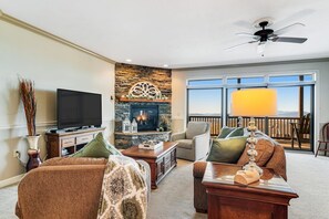 A living room with a fireplace, a television, and a view of the outdoors. - A Sweet Escape: 2br Condo in The Reserve on Sugar Mtn - Long Range Views! (Sugar Mountain)
