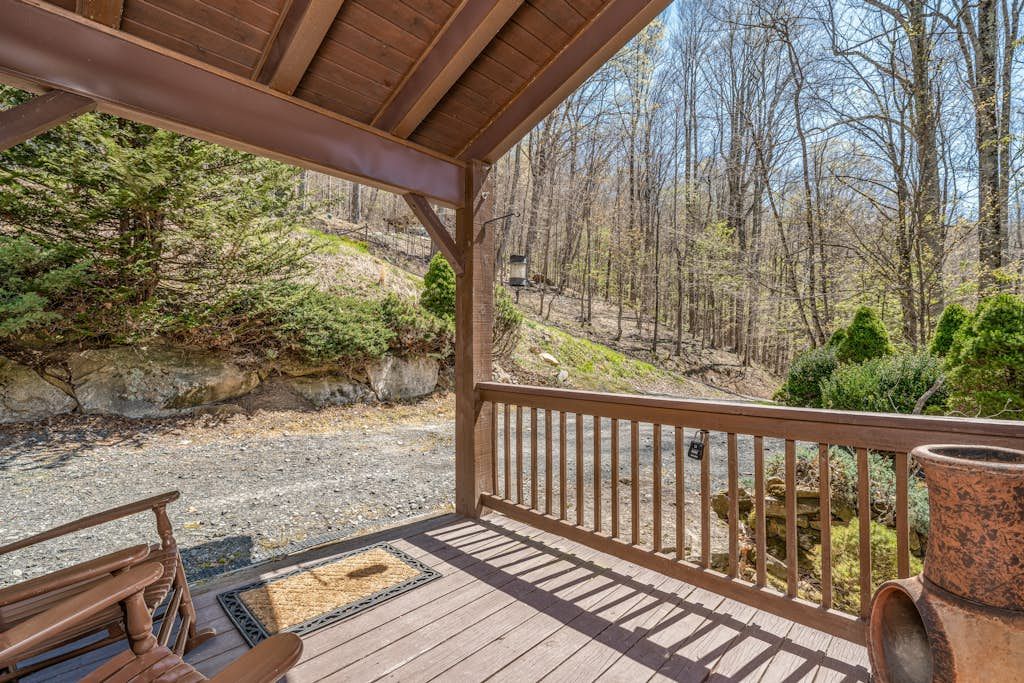 A wooden deck with a railing overlooking a forested area.