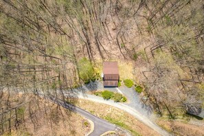 Ein Bungalow mit braunem Dach, umgeben von einer Serpentinenstraße und dichtem Grün.