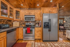 Una cocina con armarios de madera, un refrigerador de acero inoxidable, un microondas y un lavavajillas.