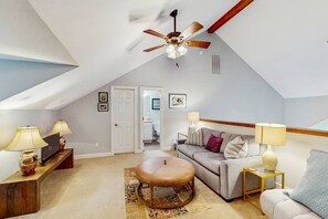A loft-style living room with a sloped ceiling, a ceiling fan, a sofa set, a coffee table, and a television on a wooden stand. - Sugar High at The Reserve II - Unobstructed Views (Banner Elk)